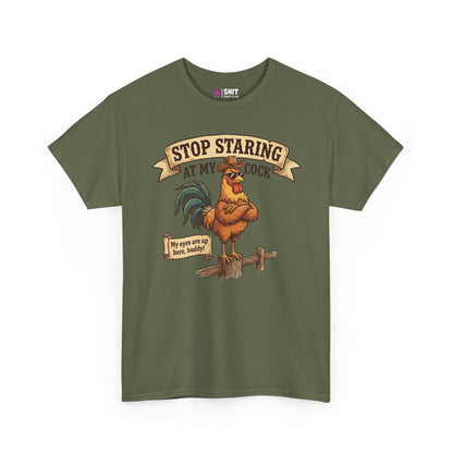 The Stop Staring at My Cock Stag Do Tee features an olive green color, an illustrated rooster on a fence, and bold text: “STOP STARING AT MY COCK” above and “My eyes are up here, buddy!” below. Perfect funny groom shirt for stag parties.