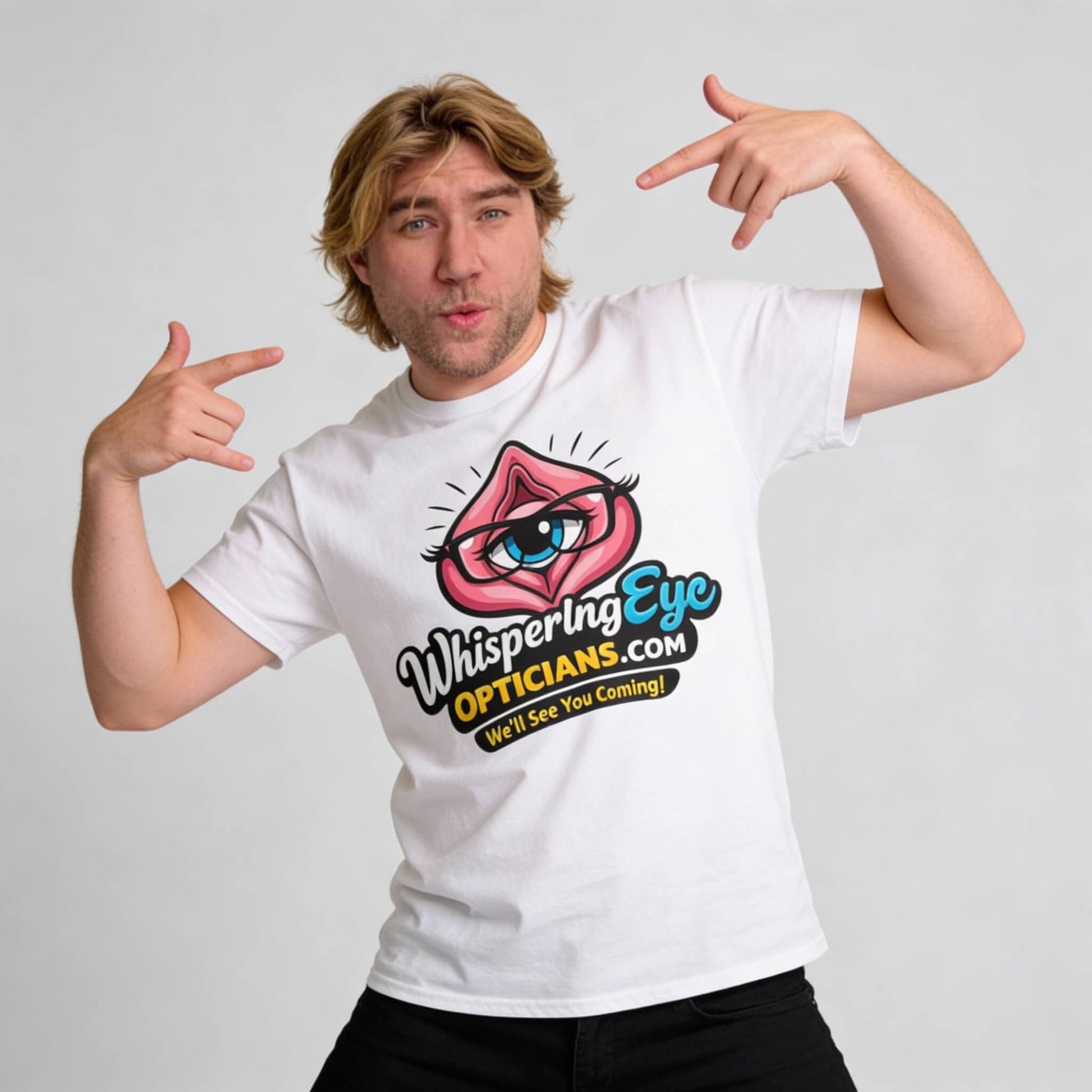 A blond man points at his Whispering Eye Opticians Logo Tee ("We'll See You Coming!") featuring a cartoon eye inside lips, against a plain light background.