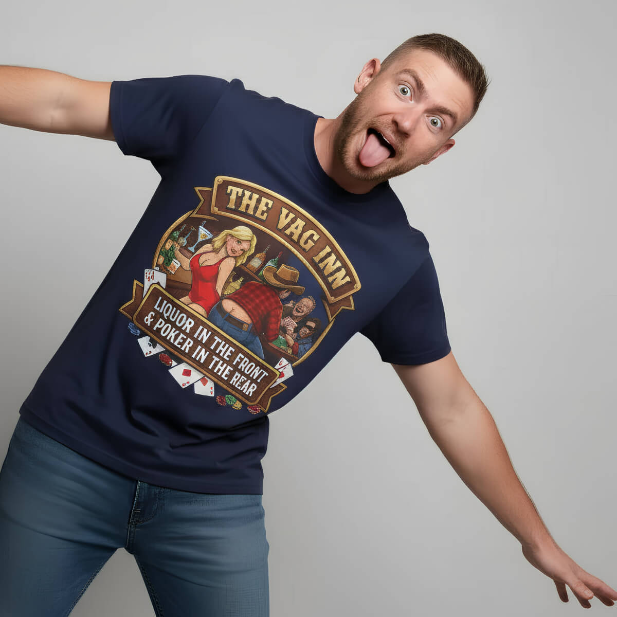 With a playful grin, a man sticks out his tongue and spreads his arms, showing off The Vag Inn "Liquor in the Front & Poker in the Rear" Tee featuring a cartoon pub scene on a navy shirt—perfect for bachelor parties.