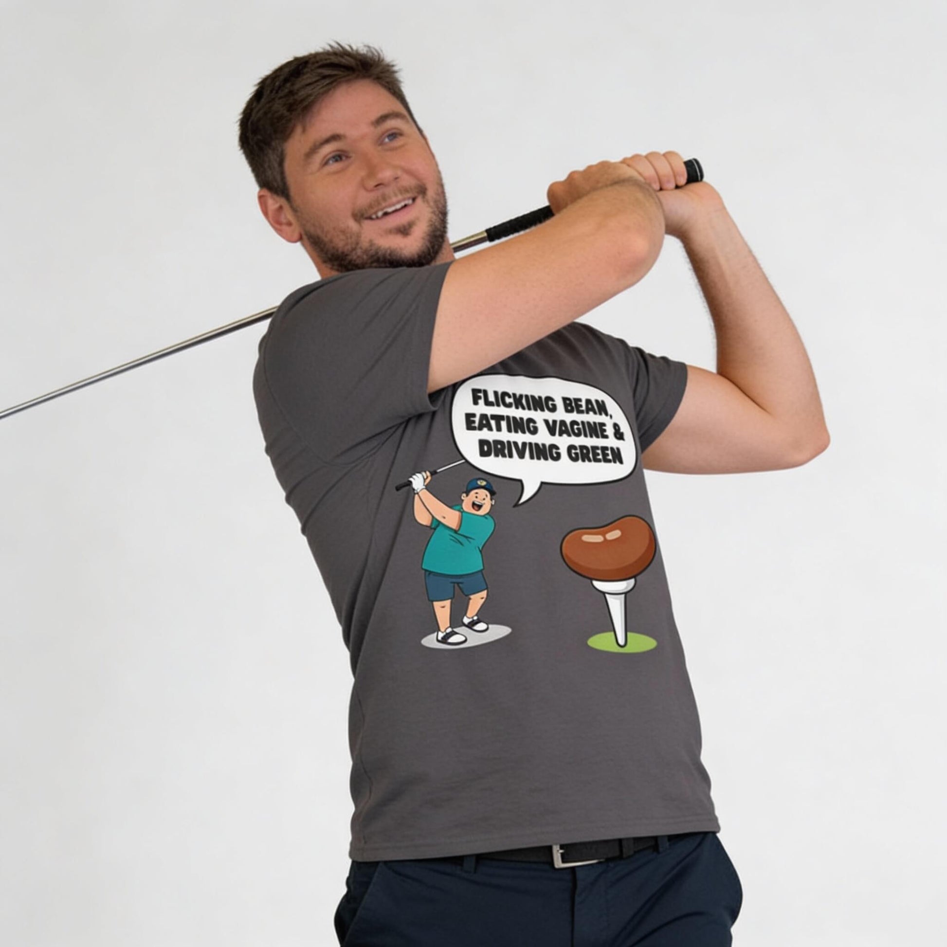 A man poses with a golf club, wearing the "Flicking Bean, Eating Vagine & Driving Green" Tee—a gray funny golf shirt featuring a cartoon golfer and tee alongside playful text.