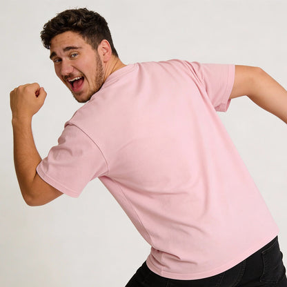 A young man in a Pussay Patrol Stag Do Tee and dark pants smiles, turning back and raising one arm playfully against a plain background.