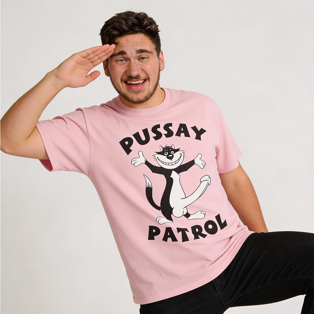 A smiling person in a pink Pussay Patrol Stag Do Tee featuring a cartoon cat and playful text salutes with one hand and raises one leg, posing against a plain background—ideal for stag do celebrations!.