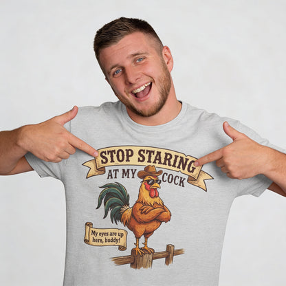 A man points at his Stop Staring at My Cock Tee, showing off its cartoon rooster in a hat and playful text—making it the perfect funny groom t-shirt or stag party shirt for your big event.