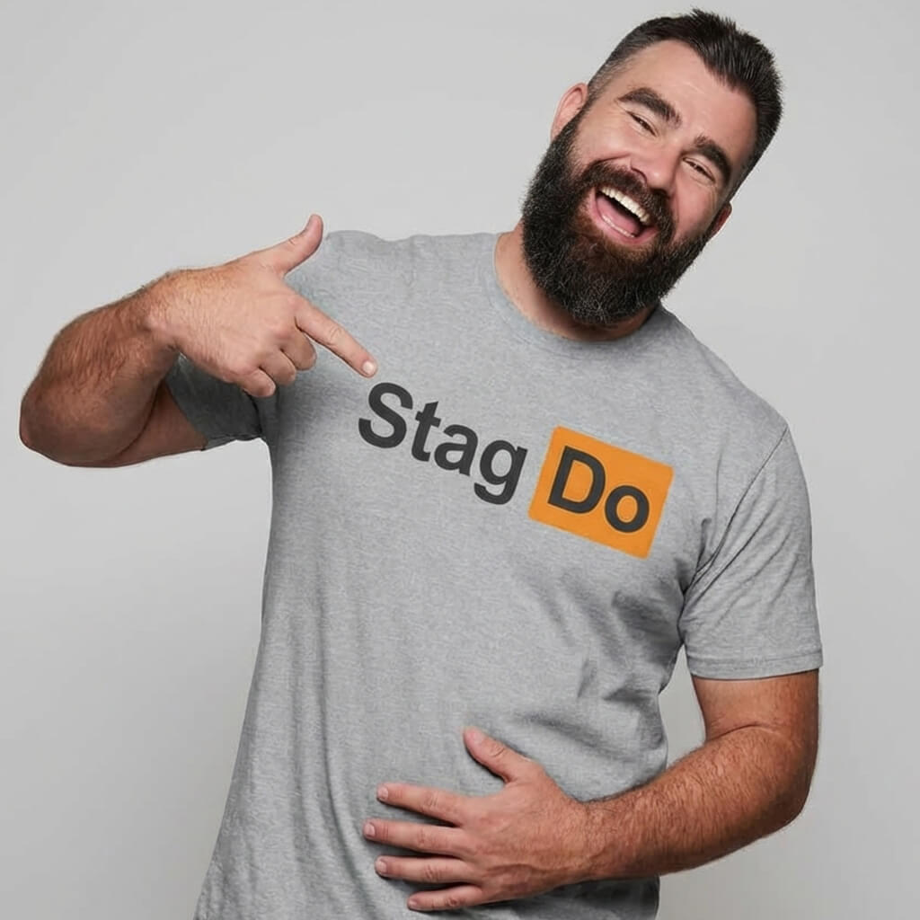 A bearded man smiles and points at his grey Stag Do PornHub Tee, which features "Stag Do" with "Do" highlighted in an orange box.