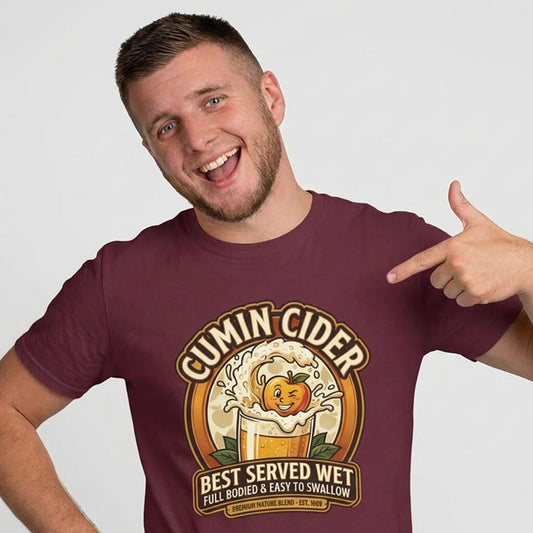 A man in a maroon Cumin Cider Stag Do Tee points to its cartoon apple splashing in cider and the words: "Cumin Cider, Best Served Wet, Full Bodied & Easy to Swallow"—making it the perfect funny stag do shirt.
