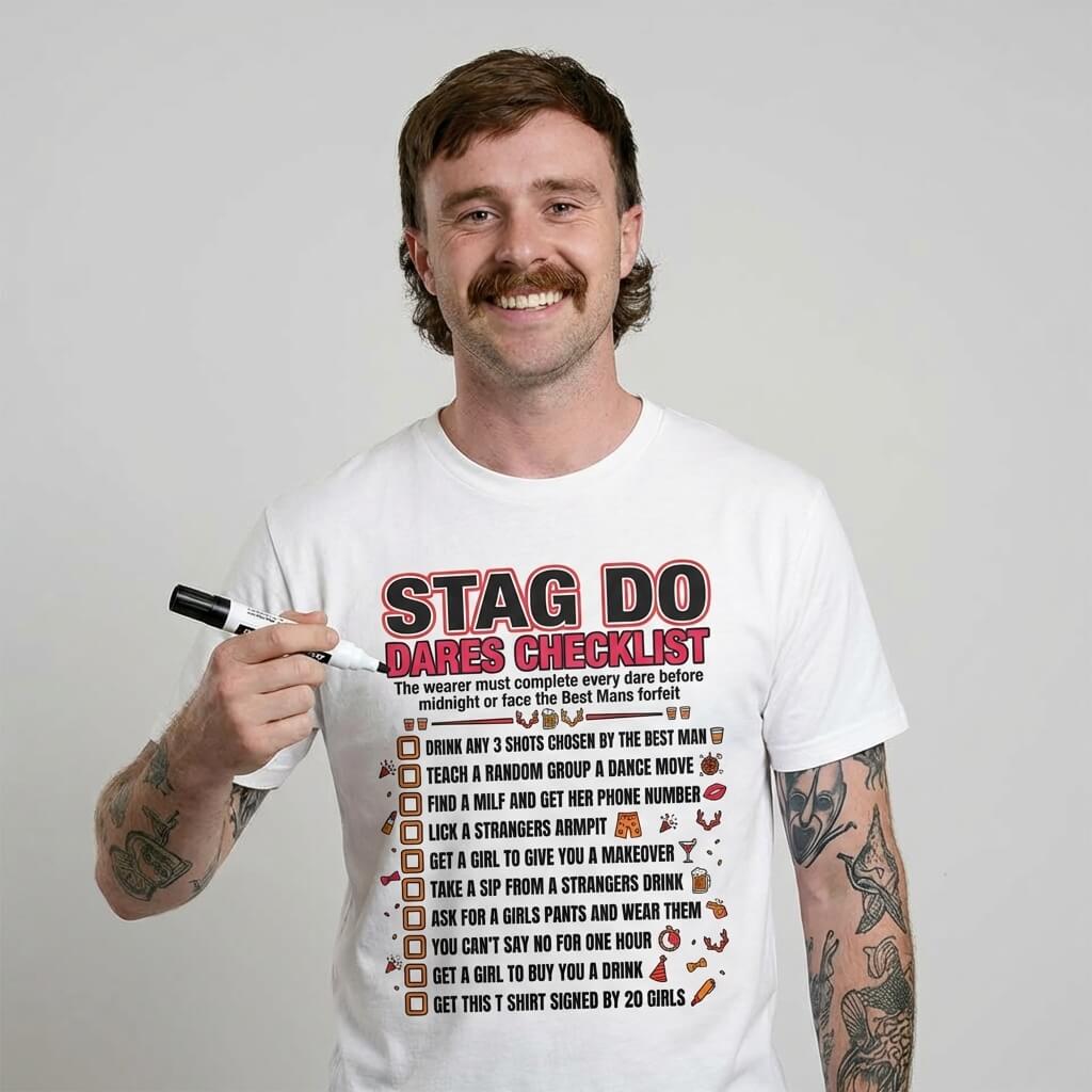 A smiling man with a mustache holds a marker and sports the Stag Do Checklist Tee, featuring a vibrant stag party checklist and funny dares—perfect for an unforgettable night out.