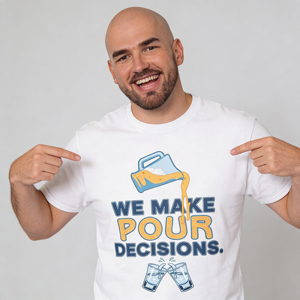 A bearded, bald man points to his We Make Pour Decisions Stag Do Tee—a white shirt with a pitcher illustration, clinking glasses, and the text "We make pour decisions." It’s a perfect funny drinking shirt for your pub crawl.