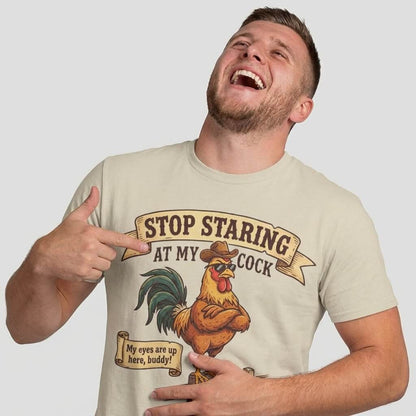 A man laughs and points at his Stop Staring at My Cock Stag Do Tee, featuring a cartoon rooster in a hat and cheeky text—making it the perfect funny groom or stag party shirt for your next big night out.