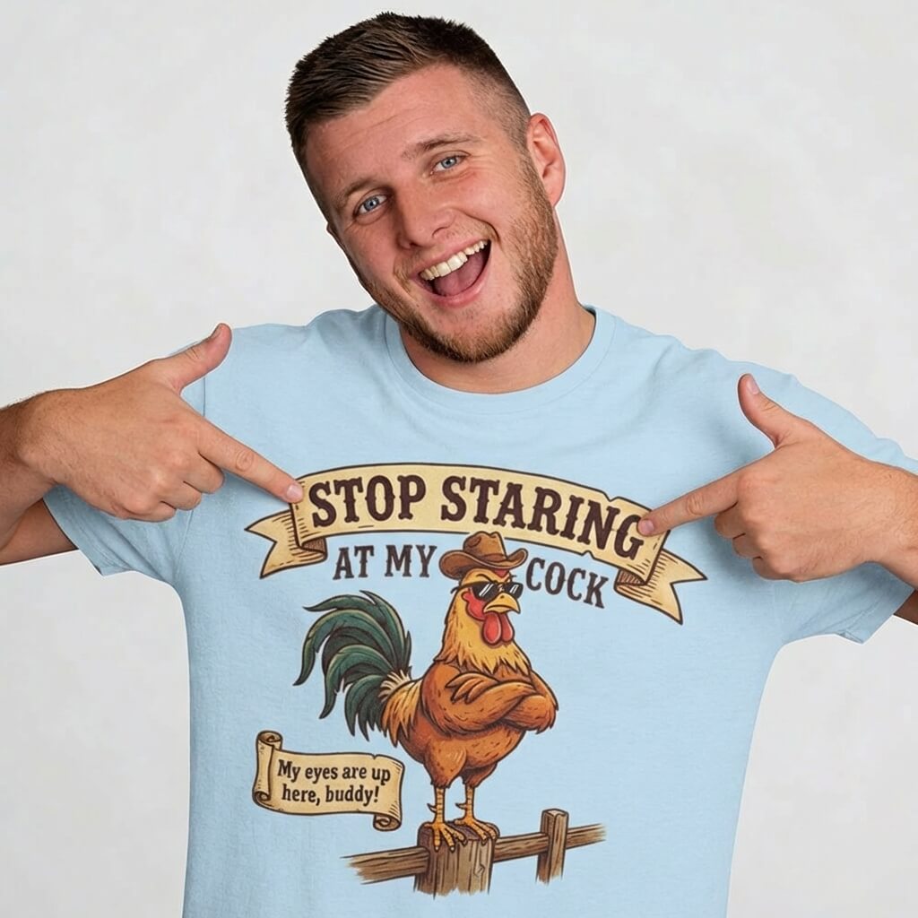A smiling man points at his light blue Stop Staring at My Cock Stag Do Tee, featuring a cartoon rooster in a hat and the phrase "STOP STARING AT MY COCK." Great for stag parties or as a funny groom t-shirt.