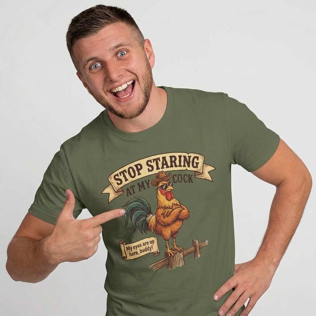 A smiling man points at his green Stop Staring at My Cock Stag Do Tee, featuring a cartoon rooster and the phrase "STOP STARING AT MY COCK"—a hilarious choice for any stag party.