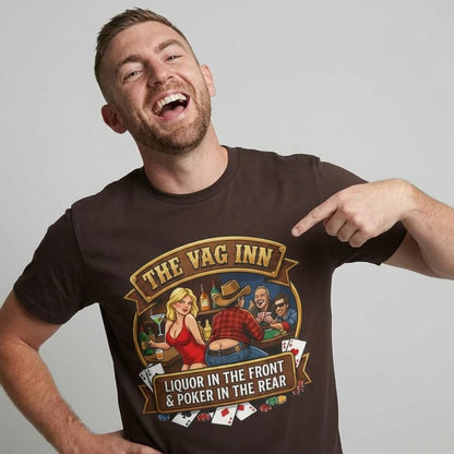 A smiling man points at his shirt, The Vag Inn Stag Do Tee, which features a cartoon bar scene and the slogan "Liquor in the Front Poker in the Rear," making it a perfect funny stag party shirt.