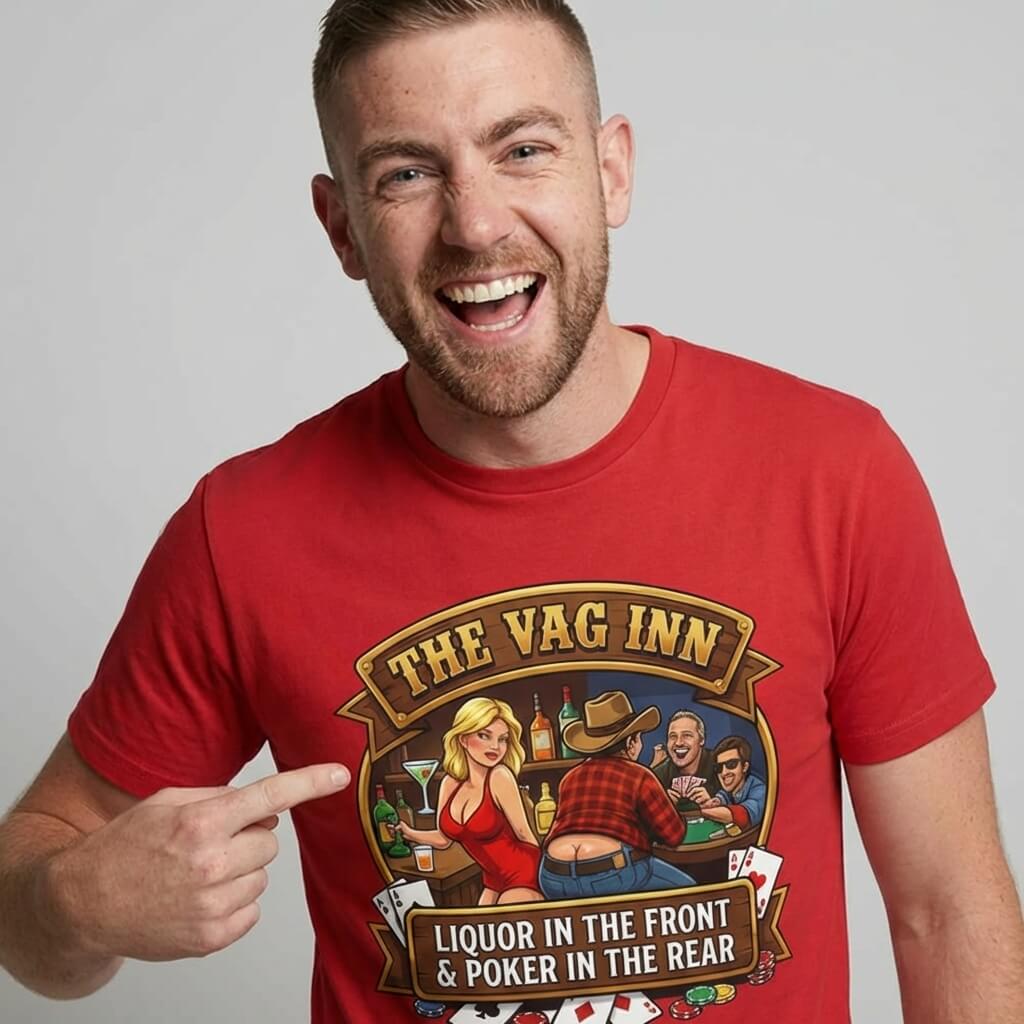 A smiling man in The Vag Inn Stag Do Tee points at his chest, showing off a cartoon bar scene and cheeky text—the perfect funny shirt for your next big night out or stag party.