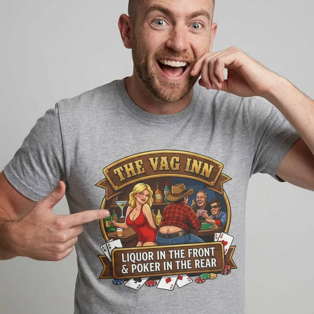 A smiling man points at his gray "The Vag Inn Stag Do Tee," featuring a cartoon poker scene in a bar. This funny pub crawl shirt reads: “THE VAG INN: Liquor in the front & Poker in the rear.”.