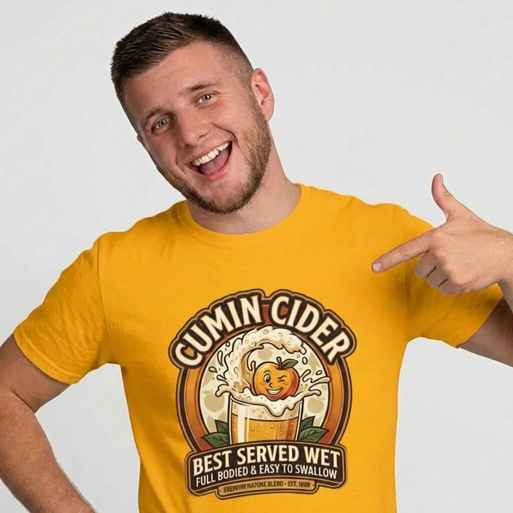 A smiling man points at the Cumin Cider Stag Do Tee, a yellow shirt with “Cumin Cider, Best Served Wet, Full Bodied & Easy to Swallow” text and a cider glass with apple graphic—the perfect stag do t-shirt.