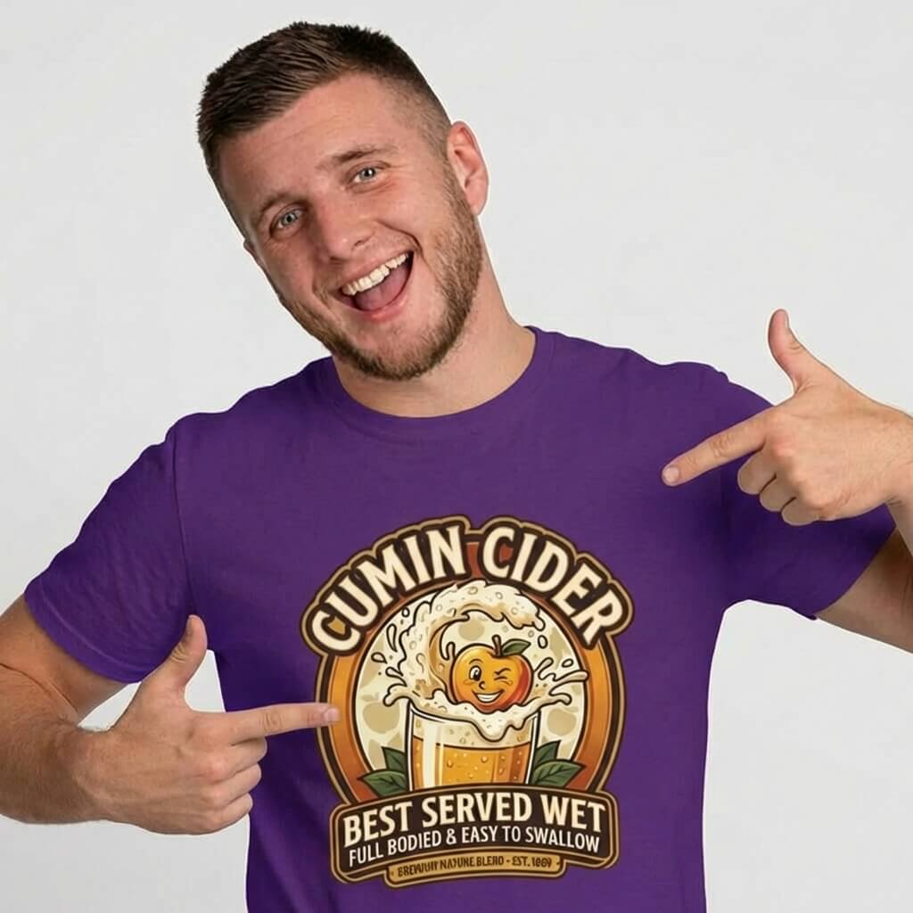 A smiling man in a purple shirt points at the Cumin Cider Stag Do Tee, featuring a cider glass with animated apple splash and the words "Best Served Wet, Full Bodied & Easy to Swallow"—a hilarious choice for any stag do.