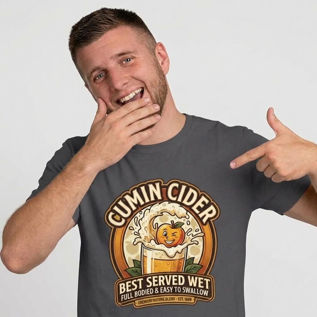A smiling man points to his Cumin Cider Stag Do Tee, featuring a cartoon cider glass with a happy apple splashing out and the text: "Cumin Cider. Best served wet. Full bodied & easy to swallow—the ultimate groom gift!.