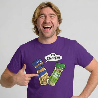 A smiling man in a purple shirt points to a cartoon spice bottle saying "IM CUMIN!" to a startled Herb Blend—making the "I’m Cumin!" Stag Do Tee the perfect funny choice for anyone after a spice-themed stag party shirt.