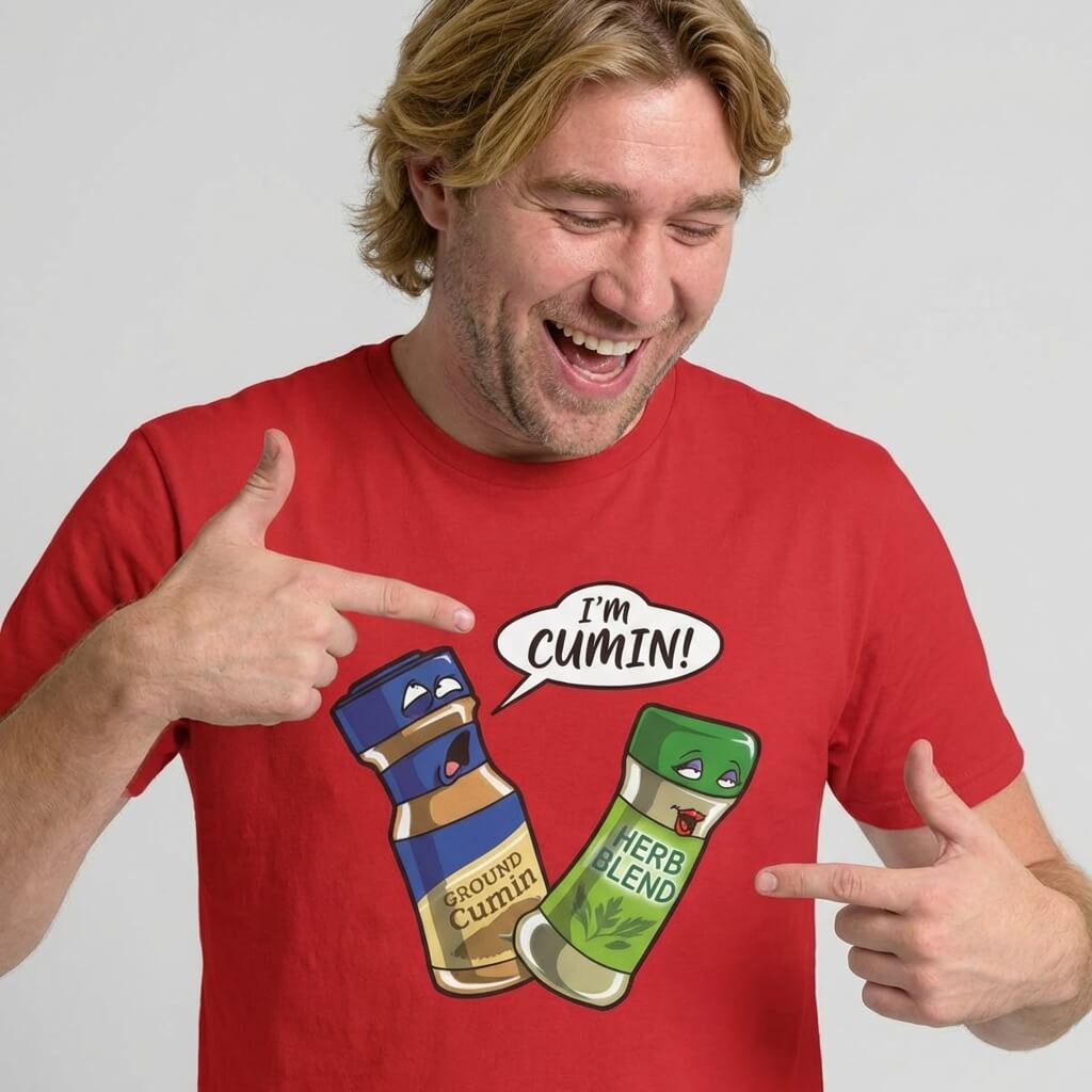 A smiling man in a red shirt points at a cartoon of two spice jars—one labeled Ground Cumin saying "I’m cumin!" and the other, Herb Blend, looking surprised. The "I’m Cumin!" Stag Do Tee is perfect for adding humor to any stag do.