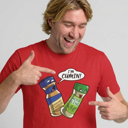A smiling man in a red shirt points at a cartoon of two spice jars—one labeled Ground Cumin saying "I’m cumin!" and the other, Herb Blend, looking surprised. The "I’m Cumin!" Stag Do Tee is perfect for adding humor to any stag do.
