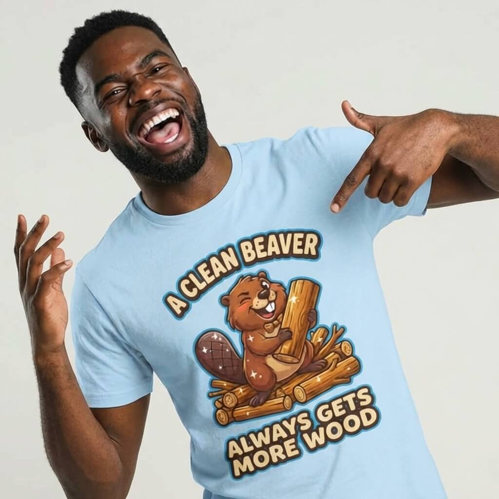 A smiling man points at his light blue "A Clean Beaver Always Gets More Wood" Stag Do Tee, featuring a cartoon beaver holding wood—a hilarious shirt perfect for stag parties.