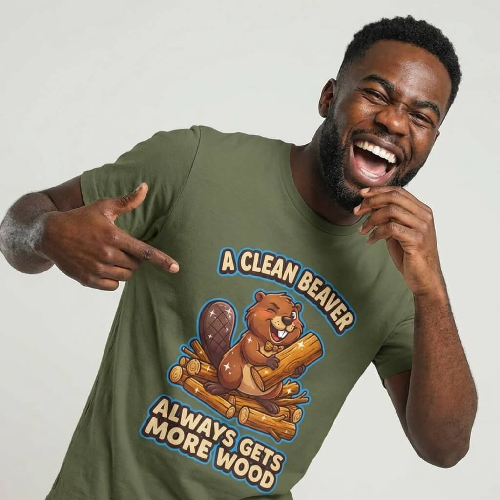 A smiling man points to his olive green "A Clean Beaver Always Gets More Wood" Stag Do Tee, featuring a cartoon beaver holding a log and the humorous slogan.