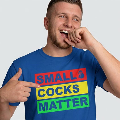 A smiling man points to his blue Small Cocks Matter Stag Do Tee, featuring bold, colorful text boxes and a small rooster icon—perfect for stag do humour and body confidence.