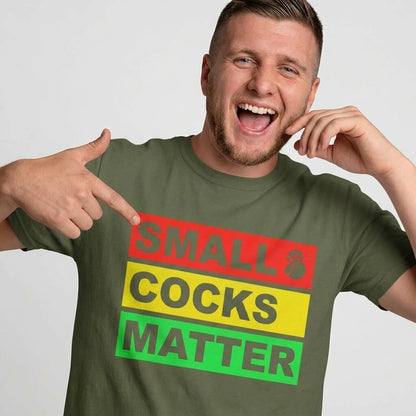 A smiling man with short hair points to his green Small Cocks Matter Stag Do Tee, which displays bold red, yellow, and green blocks—a playful nod to body confidence and classic stag do humour.