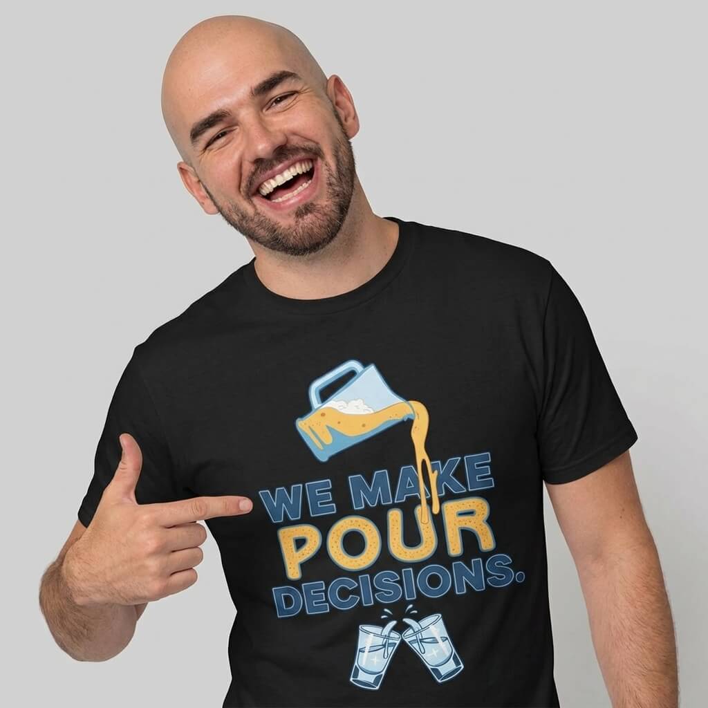 A bearded man smiles and points to his black "We Make Pour Decisions Stag Do Tee," featuring a beer pitcher graphic and two clinking beer glasses below the playful text.