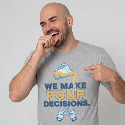 A smiling bald man points and laughs at his gray "We Make Pour Decisions Stag Do Tee," featuring a beer pitcher pouring into two clinking glasses.