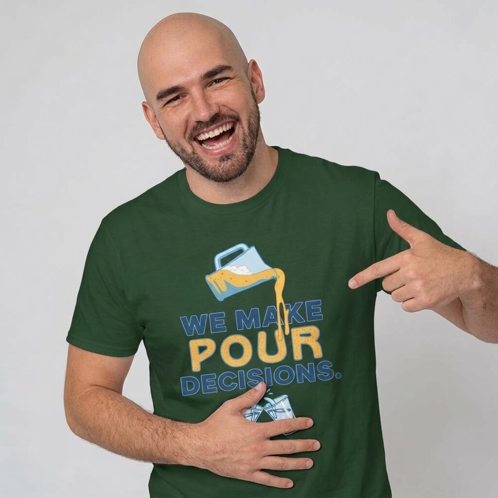 A smiling bearded bald man points to his green "We Make Pour Decisions Stag Do Tee," which features a milk jug illustration pouring liquid and the phrase "We make pour decisions.