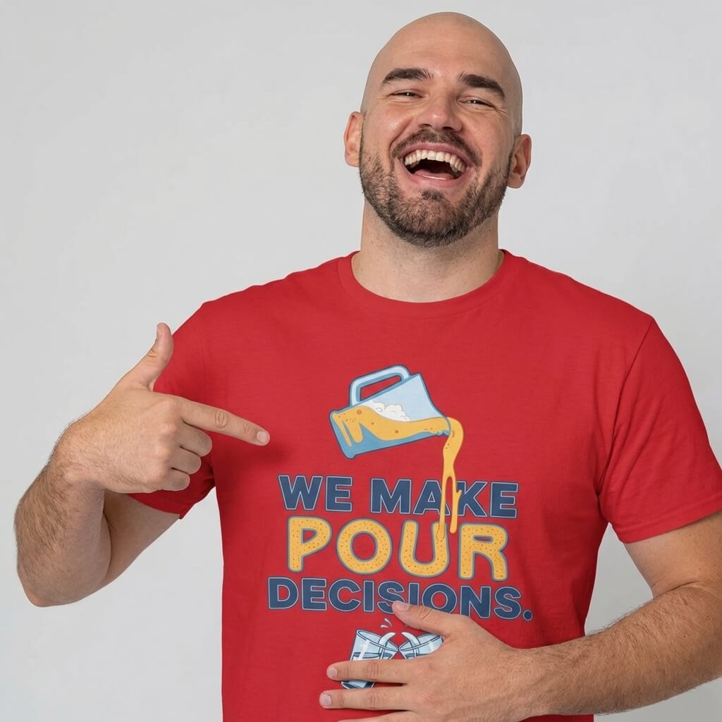 A smiling man in a red shirt points to his "We Make Pour Decisions Stag Do Tee," featuring text and a drink being poured over ice cubes.