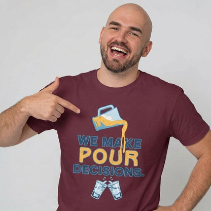 A bald, bearded man smiles and points to his We Make Pour Decisions Stag Do Tee, featuring a maroon design with a spilling beer mug graphic and the text "We make pour decisions" above two clinking glasses.