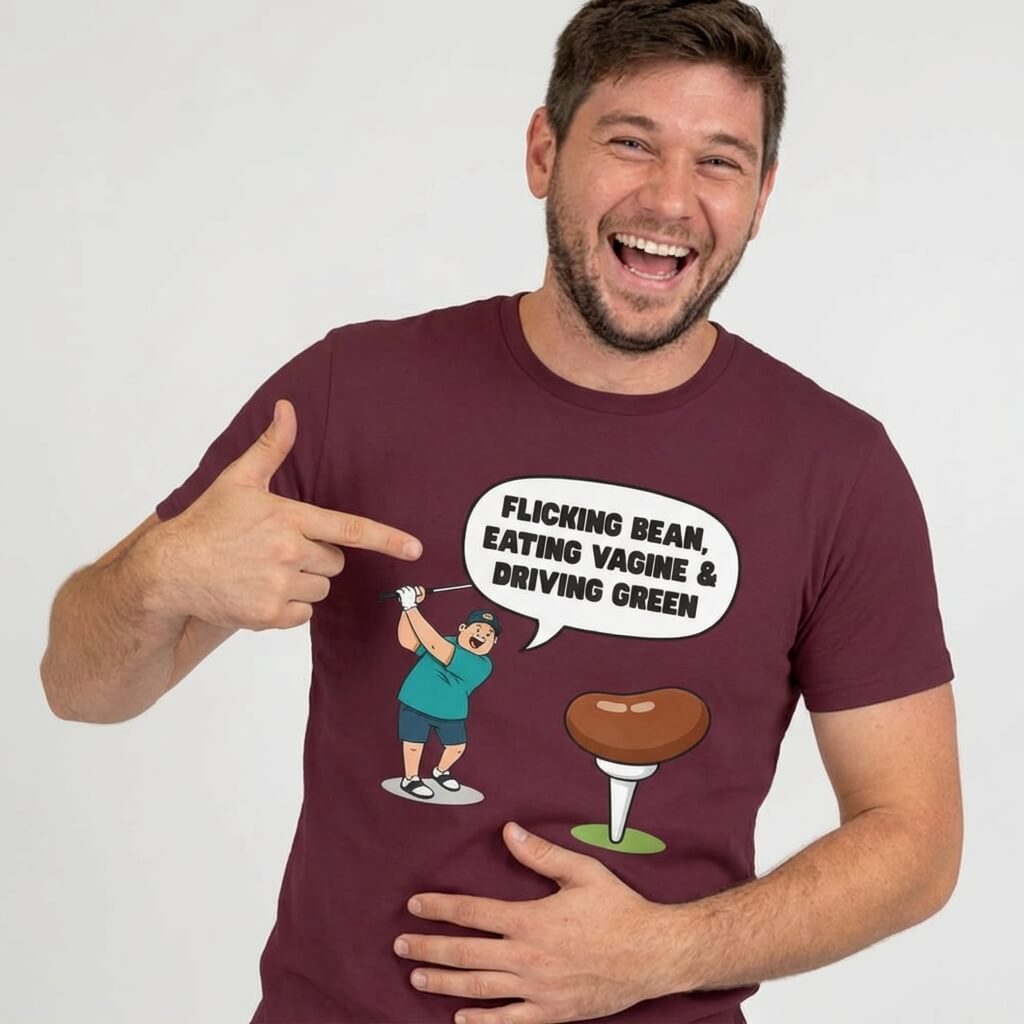 A man in a maroon "Flicking Bean, Eating Vagine & Driving Green" Tee points at a cartoon graphic featuring the same phrase in a speech bubble, an illustrated character, and a golf tee with a bean.