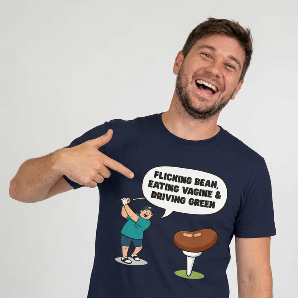 A smiling man points at his “Flicking Bean, Eating Vagine & Driving Green” Tee, a navy shirt with a cartoon golfer and bean—this funny golf shirt is perfect for stag dos.