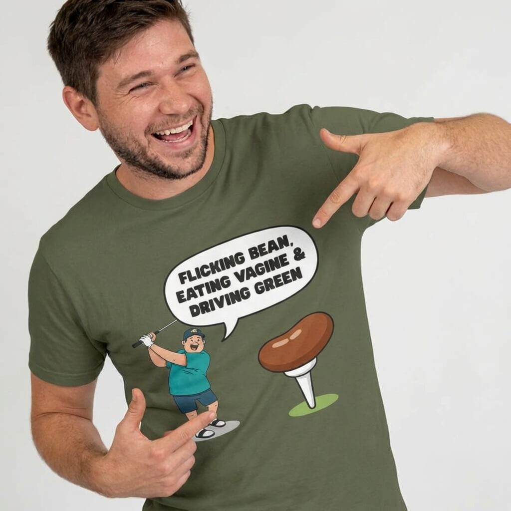 A smiling man shows off his green "Flicking Bean, Eating Vagine & Driving Green" Tee with a cartoon golfer and large brown tee—ideal as a rude golf shirt or stag do gift.