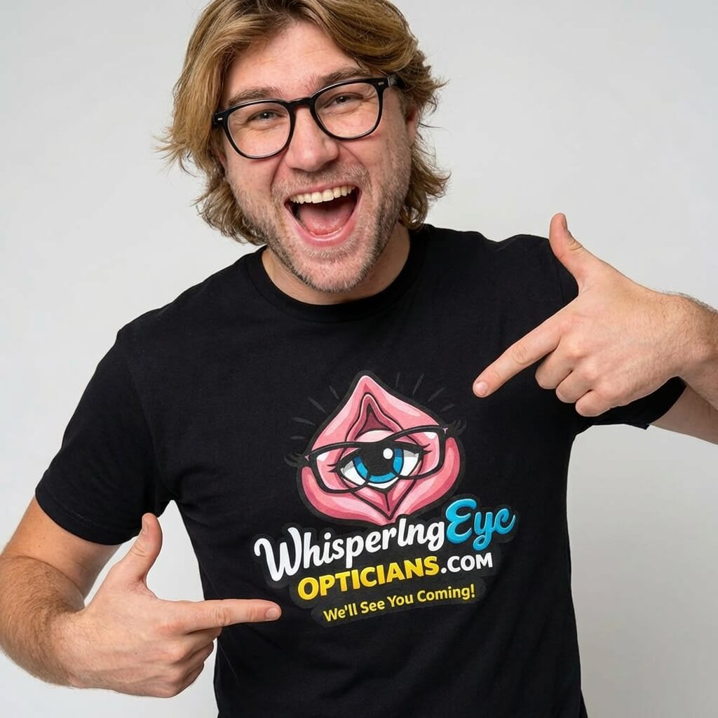 A smiling man with glasses points at his Whispering Eye Opticians Logo Tee (We'll See You Coming!)—a cheeky, fun t-shirt featuring a cartoon eye and bold pink design, perfect for adding humor to any stag do or night out.