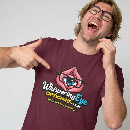 A smiling man in glasses points at his Whispering Eye Opticians Logo Tee (We'll See You Coming!), featuring a cartoon eye in lips. It's the perfect rude t-shirt for fun occasions and guaranteed to get laughs.