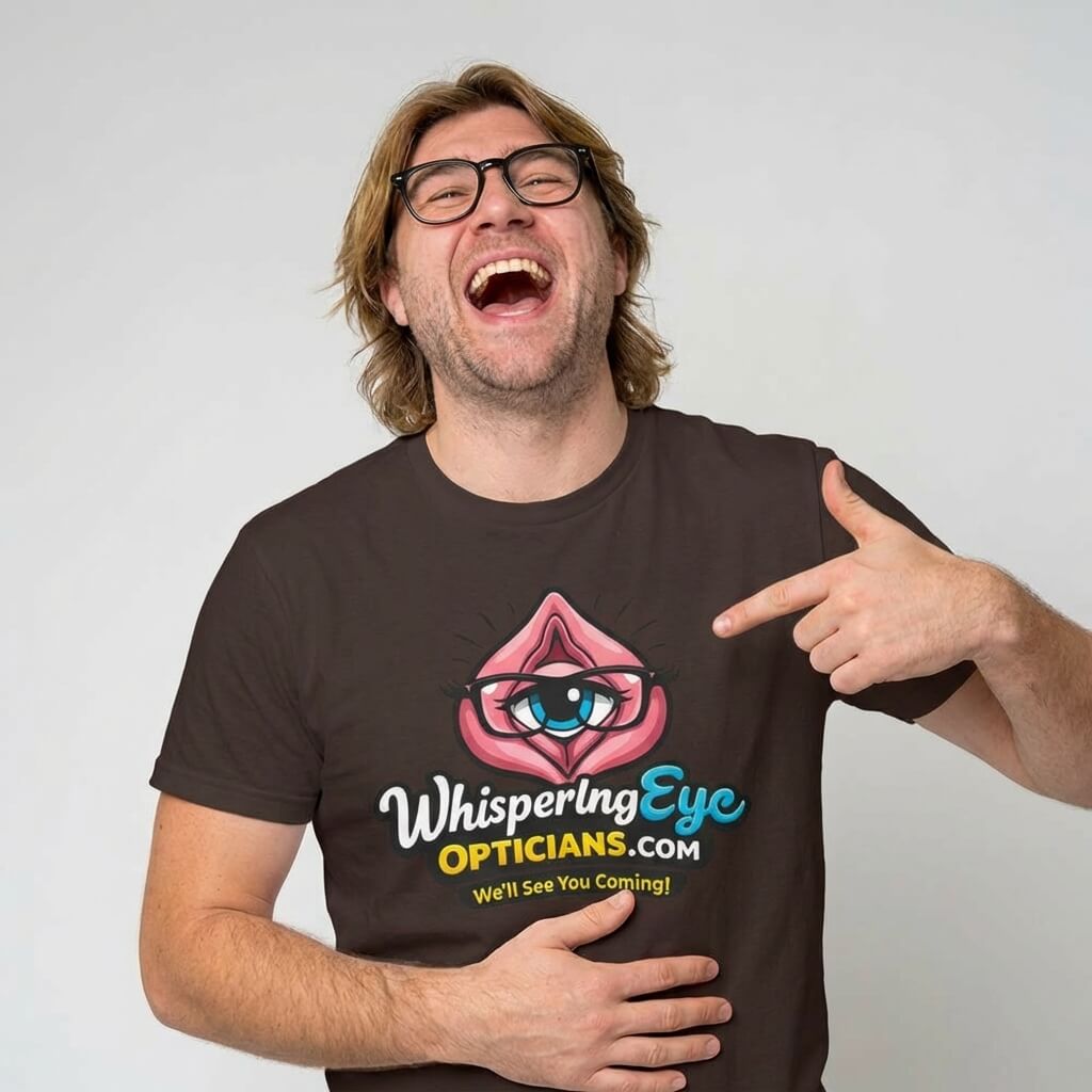 A man with shoulder-length hair and glasses laughs, pointing at his Whispering Eye Opticians Logo Tee (We'll See You Coming!)—the perfect stag do t-shirt featuring a cheeky cartoon eye in pink lips.