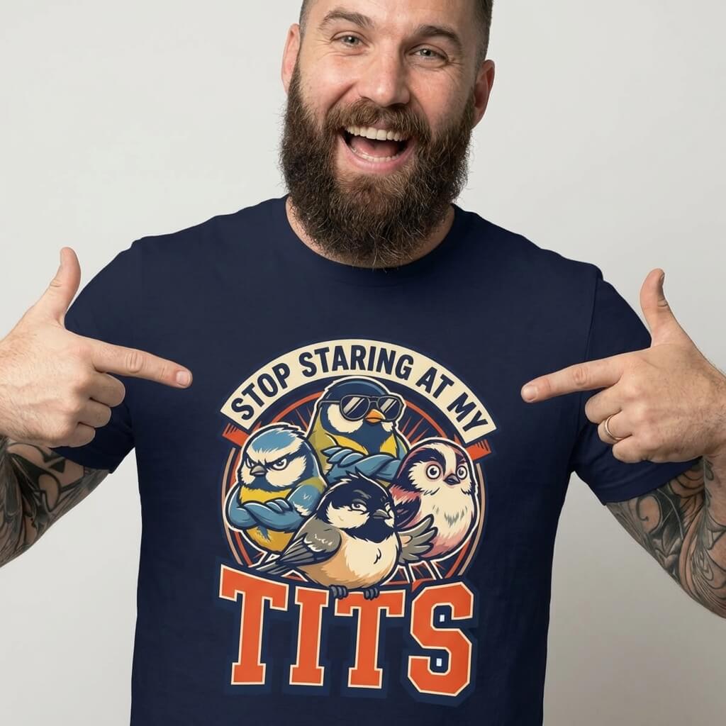 A bearded man smiles and points at his “Stop Staring at My Tits” Stag Do Tee, a navy blue shirt with cartoon birds—a funny groom gift or stag do outfit.