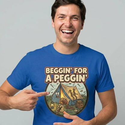 A smiling man points at his Beggin' for a Peggin' Camping Tee, which features two silhouetted people in a tent with camping gear—making it a hilarious festival outfit or cheeky gift idea.
