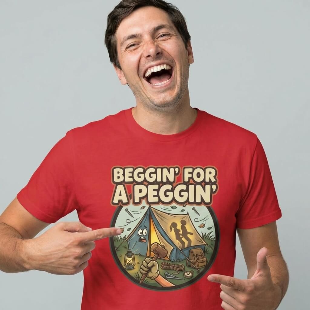 A smiling man in a red "Beggin' for a Peggin' Camping Tee" with a cartoon camp scene—two tents, campfire, and figures—points at this funny t-shirt, perfect as a rude gift or cheeky outfit for festivals.