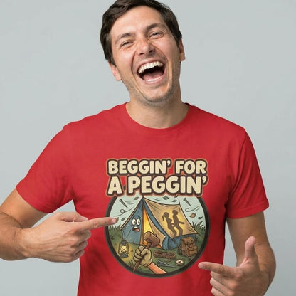 A smiling man in a red "Beggin' for a Peggin' Camping Tee" with a cartoon camp scene—two tents, campfire, and figures—points at this funny t-shirt, perfect as a rude gift or cheeky outfit for festivals.