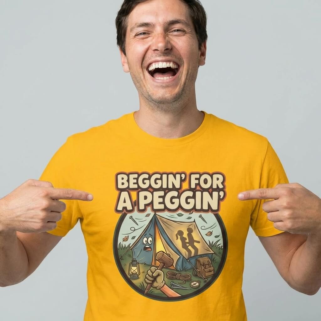 A man in a yellow shirt points to his "Beggin' for a Peggin' Camping Tee," featuring the phrase above a cartoon camp scene with two shadowy figures in a tent—ideal for festival looks or as a rude gift.