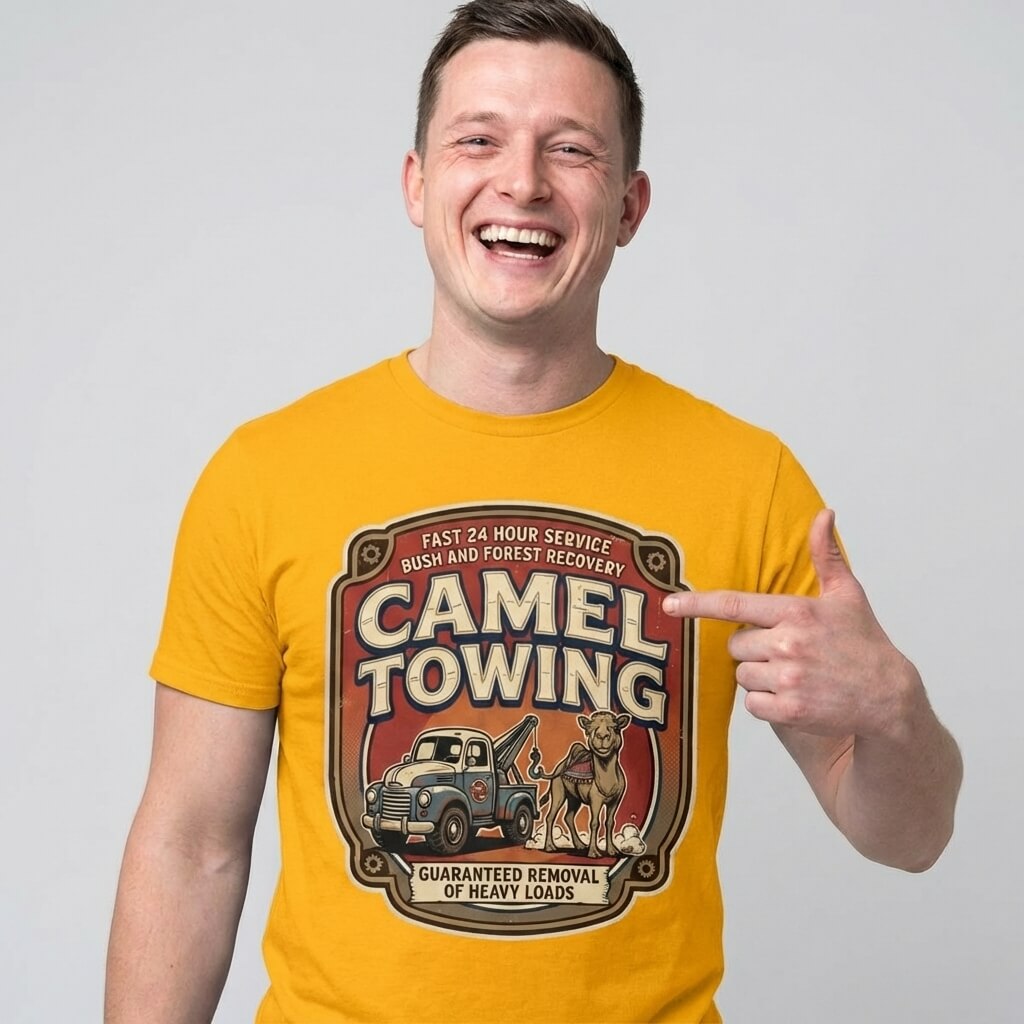 A smiling man wears the Camel Towing Funny Tee, featuring a tow truck and camel graphic—making it a perfect novelty gift for anyone with a sense of humor.