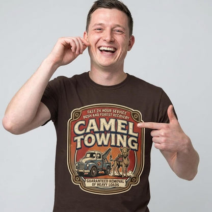 A smiling man points to his Camel Towing Funny Tee, a novelty graphic shirt with a vintage tow truck, camel illustration, and “Camel Towing: Guaranteed Removal of Heavy Loads”—the perfect funny gift.
