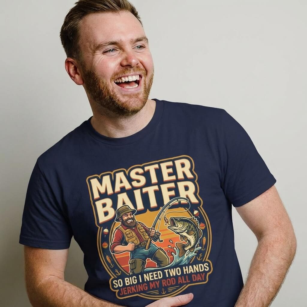 A bearded man wears the Master Baiter Rude Fishing Tee, a navy shirt featuring a cartoon fisherman with a big fish and the cheeky text "So big I need two hands jerking my rod all day"—a hilarious, bold fishing t-shirt for any angler.