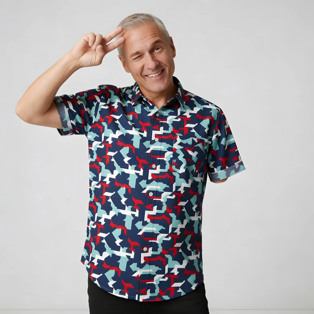 A smiling older man with gray hair sports the Combat2Coffee Army Camo Shirt, flashing a peace sign by his forehead. Set against a simple light background, he embodies the positive spirit of the military community.