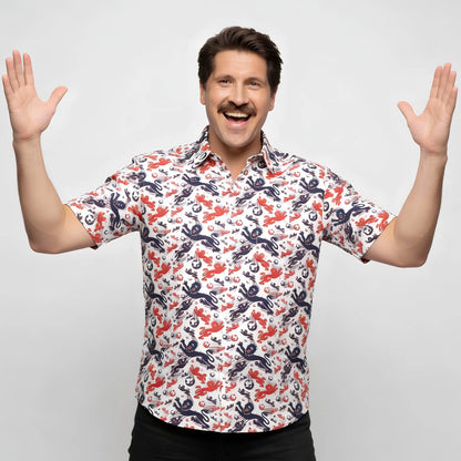 A smiling man with a mustache raises both hands enthusiastically, wearing an England Football Hawaiian Shirt featuring a vibrant red and blue crab and octopus print on a white background.