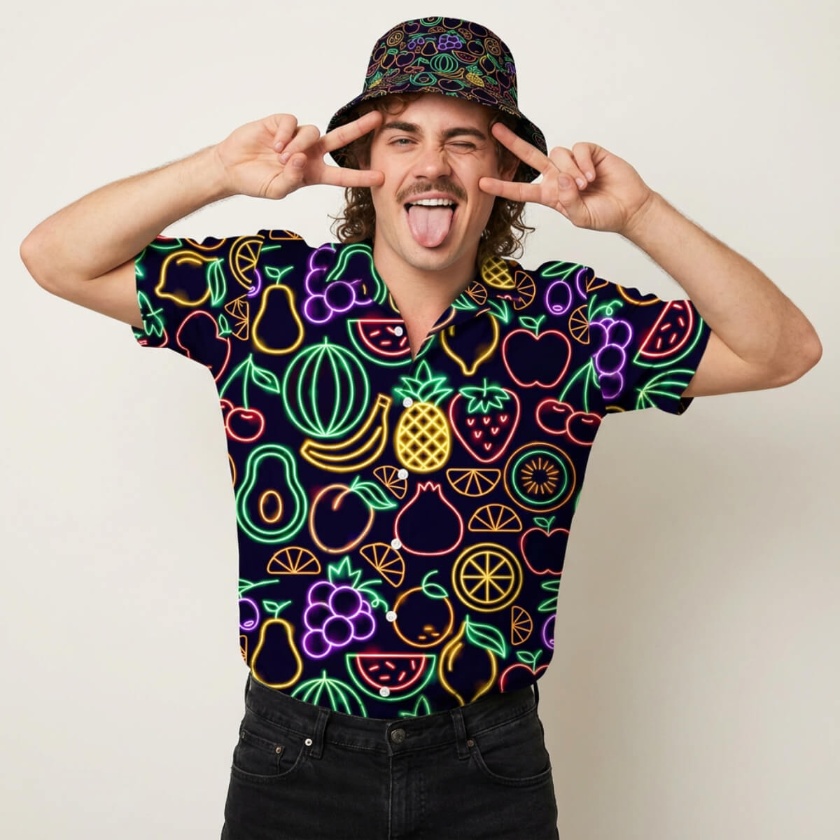 Smiling and flashing peace signs, a mustached person in the vibrant Fluorescent Fruit Fiesta Shirt poses against a plain background, playfully sticking out their tongue.