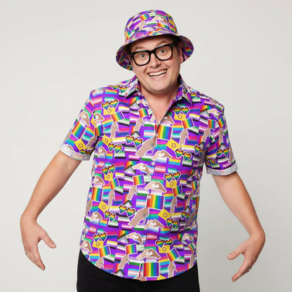A person in glasses and a matching bucket hat smiles at the camera with arms raised and fingers spread, wearing the LGBTQ Pride Shirt, against a plain white background.